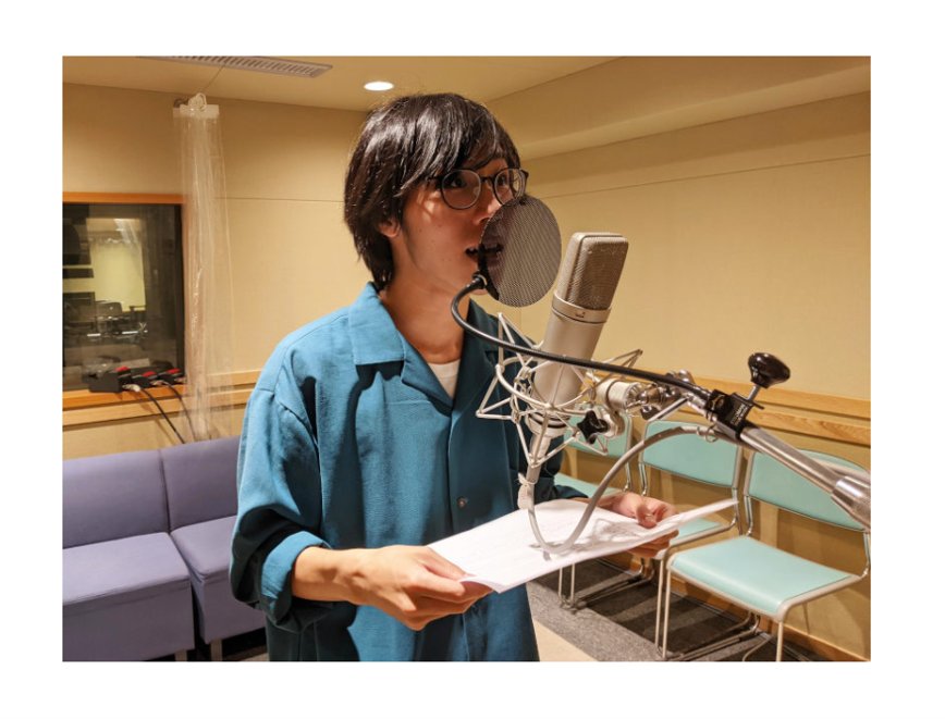 レコーディングスタジオでマイクの前に立ち、台本を手に声を収録するメディアーノ様のたかやさん